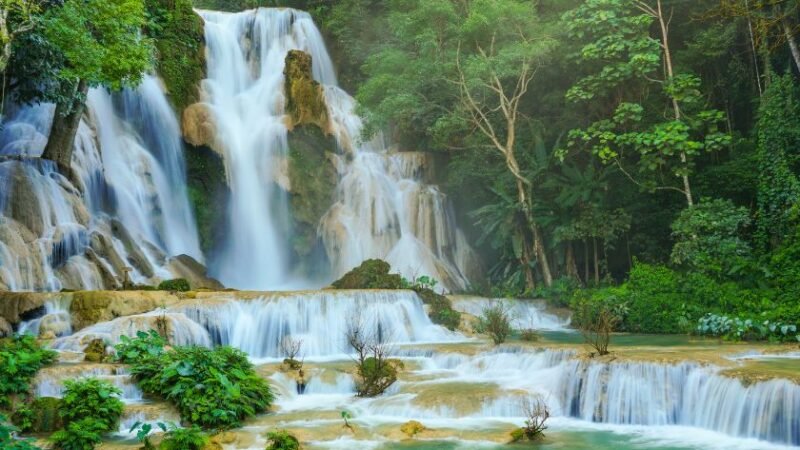 Cascade tropicale à plusieurs niveaux entourée de végétation luxuriante et d’eau turquoise.
