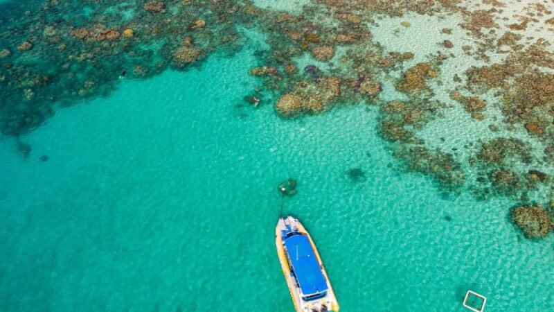 Bateau amarré sur des eaux turquoise près d’un récif corallien.