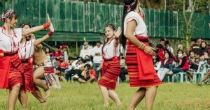 Jeunes femmes en costume traditionnel exécutant une danse folklorique devant un public, symbole de patrimoine culturel vivant, de diversité et de tourisme respectueux des communautés locales.