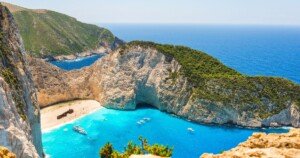 Baie de Navagio en Grèce avec son sable doré, ses falaises blanches, une mer turquoise éclatante et une épave échouée emblématique.