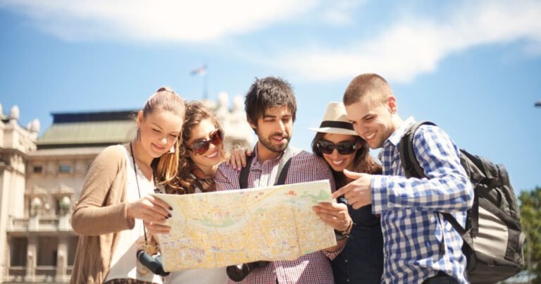 Groupe de jeunes voyageurs souriants consultant une carte en ville, symbole de découverte, d’aventure et de tourisme collaboratif.