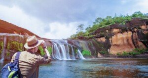 Voyageur observant une cascade tropicale depuis la rive.