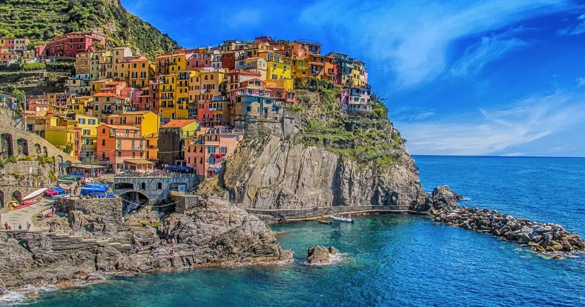 Vue panoramique sur le village coloré de Manarola perché sur une falaise, surplombant la mer Méditerranée, joyau des Cinque Terre en Italie et symbole de tourisme durable en milieu côtier.