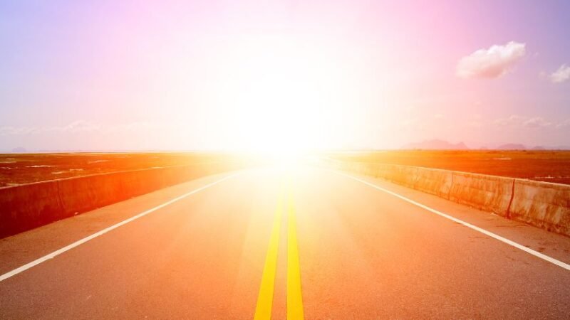 Route droite s’étendant vers l’horizon avec un soleil éclatant, symbolisant un voyage transformateur et lumineux.
