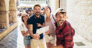 Groupe de jeunes touristes souriants explorant une ville avec une carte.